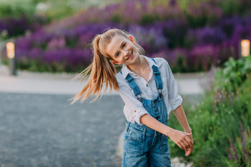 Smiling little girl in white shirt and jeans short playing in the park