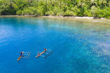 Villagers paddle their outrigger canoe in the warm, blue waters surrounding the island of New Britain in Papua New Guinea. This area is part of the Coral Triangle due to its high marine biodiversity. - Powered by Adobe