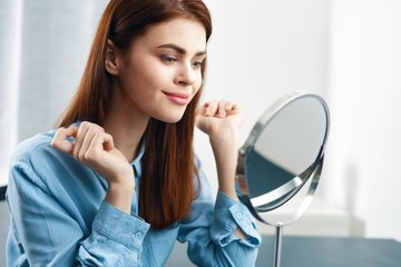 portrait of young woman applying makeup in mirror