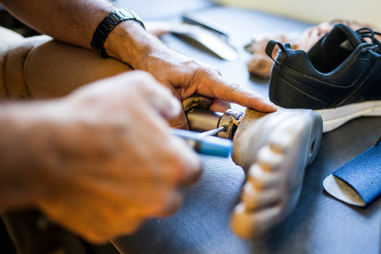 Unrecognizable prosthetic engineer reviewing the prosthesis of a patient and improving the material in his workshop
