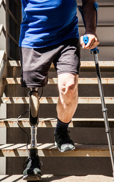 unrecognizable man amputated with crutches testing his new leg prosthesis going down stairs