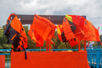 Life jacket for swimming. Orange life jacket. Orange life jacket hanging on the hanger.