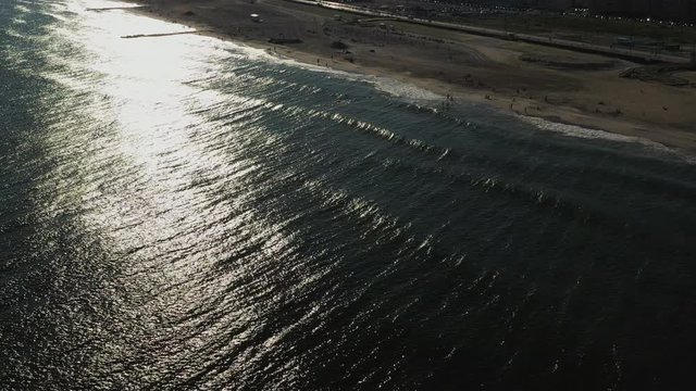 aerial drone crane shot over the ocean, rise up as the camera tilts down over the water, focusing on the glistening sunshine on the water