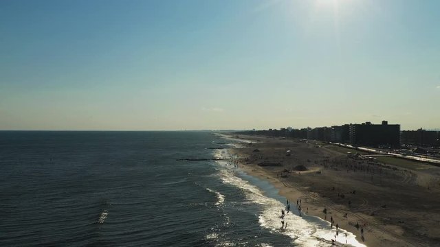 slow rise up over the ocean as the sun sets, over a beach scene to reveal a bay in the distance with the sun shining on the waters