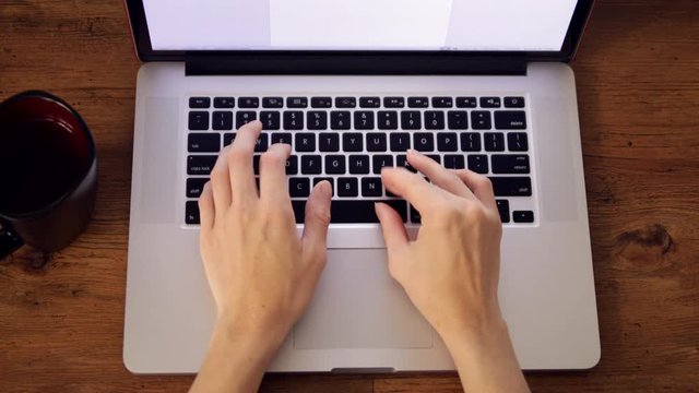 hands typing on laptop keyboard overhead