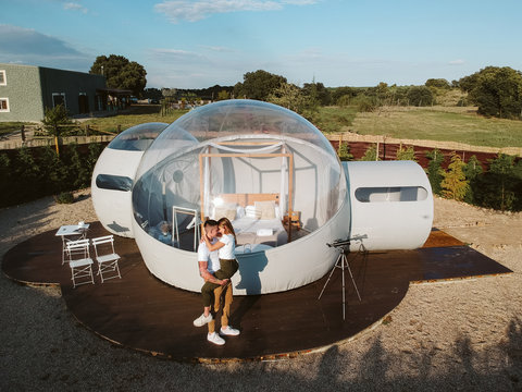 aerial view of a Young couple kissing by unusual bubble hotel