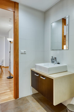 Interior of bathroom in minimalist modern style with mirror and sink on wooden stand