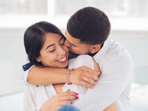 Young handsome man with closed eyes hugging attractive smiling woman