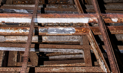 Stack of old industrial iron and rebar with rust and peeling paint.