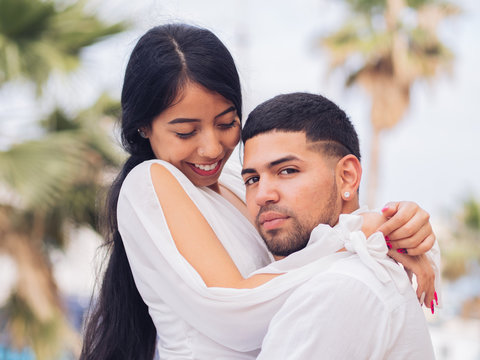 Side view of lovely young couple in light clothes bonding and hugging with love and tenderness on dock in port