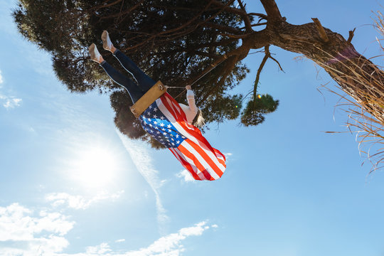 Young girl celebrating the 4th of July with the American flag on a swing
