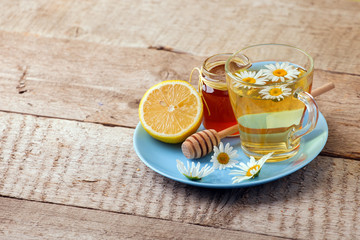 Chamomile flowers and chamomile tea. Chamomile tea in cup with flowers, honey and lemon, close-up. Seasonal treatment, alternative medicine remedy