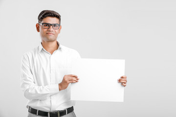 Young Indian business executive showing blank sign board over white background