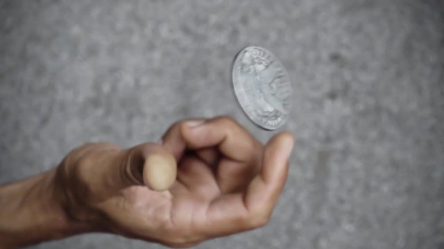 slowmotion shot tossing coin to flip on heads or tails