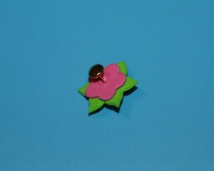 handmade pink flower with green leaves of foamiran lies on a blue background