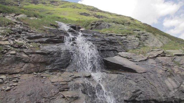 A hand held shot of a small waterfall pouring through the rocks in the mountains, Livigno, Forcola di Livigno, Livigno Pass