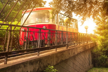 Naklejka premium The Red Car of the Funicular rises in the bright sunlight of an evening sunset in the capital of the Russian Far East, Vladivostok