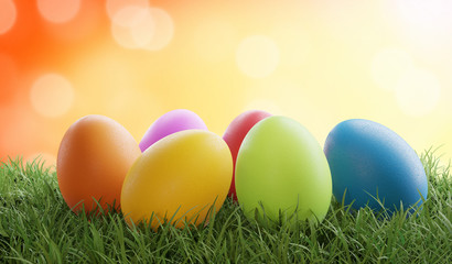 Fototapeta na wymiar colored Easter eggs on grass 3d-illustration with bokeh orange background