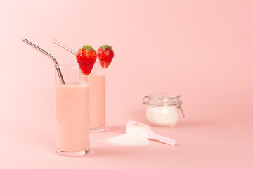 Two strawberry smoothies and a jar with collagen powder or protein.