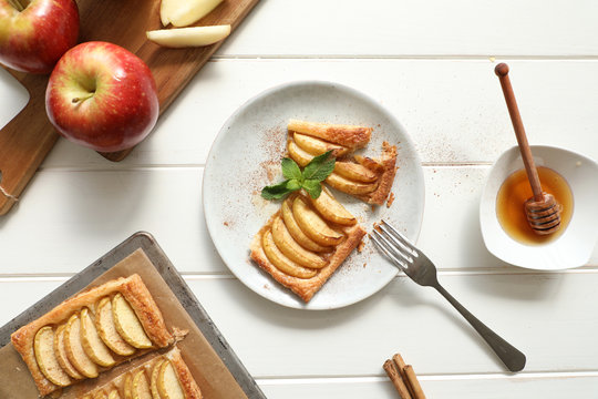 From above piece tasty apple pie with honey and mint leaves with cinnamon placed on plate over white table
