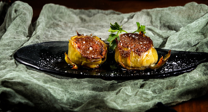 Tasty stuffed artichokes with salt on black background
