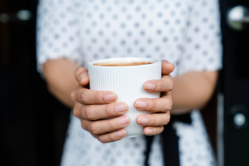 Closeup image of a beautiful Asian woman holding and drinking hot coffee with feeling good in vintage cafe