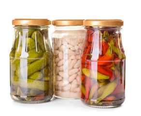 Jars with different canned vegetables and beans on white background