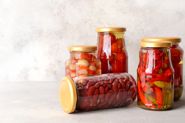 Jars with different canned vegetables and beans on grey table