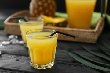 Glass of tasty pineapple juice on dark table