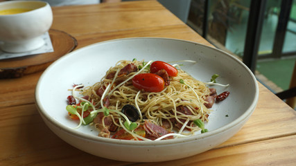 Bacon and dry chili spaghetti serving with fresh tomato on timber table