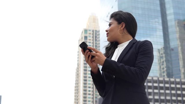 Hispanic businesswoman using smartphone searching for location in the city