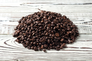 Heap of roasted coffee beans on old rustic white wooden table. Copy space for text
