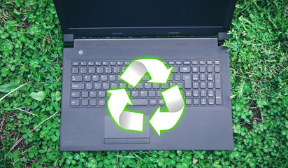Black laptop with Recycle sign in the grass.