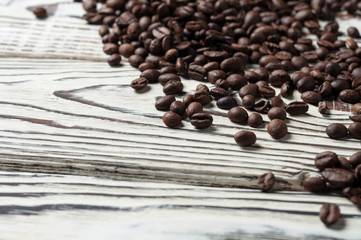 Lot of roasted coffee beans scattered on old rustic white wooden table. Copy space for text