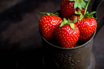Ripe and juicy strawberries in old rustic metal cup. Selective focus. Shallow depth of field. 