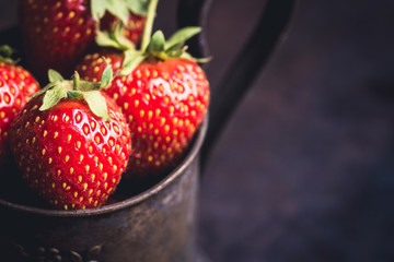 Ripe and juicy strawberries in old rustic metal cup. Selective focus. Shallow depth of field. 