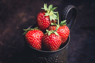Ripe and juicy strawberries in old rustic metal cup. Selective focus. Shallow depth of field. 