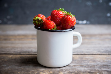 Ripe and juicy strawberries in old rustic metal cup. Selective focus. Shallow depth of field. 