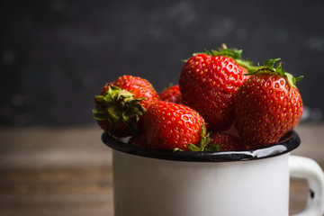 Ripe and juicy strawberries in old rustic metal cup. Selective focus. Shallow depth of field. 