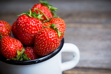 Ripe and juicy strawberries in old rustic metal cup. Selective focus. Shallow depth of field. 