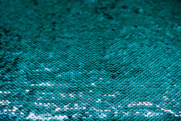 Shiny iridescent turquoise sequins on fabric. Abstract festive sparkling background