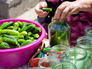 Grandma closes pickled cucumbers in the banks for the winter,the process of pickling  small fresh cucumbers in jar