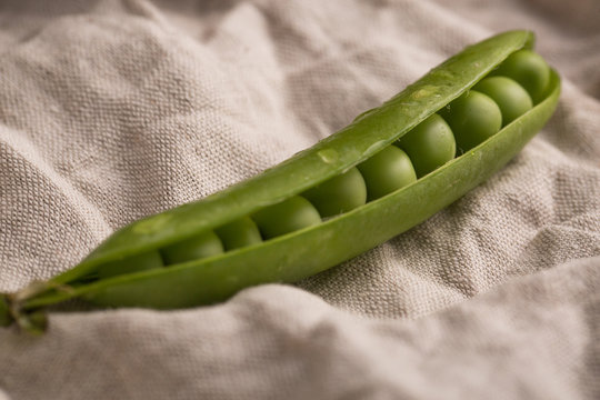 Peeled fresh peas and pea pods on dark background