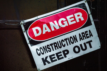 Naklejka premium Crooked old metal warning sign that reads DANGER CONSTRUCTION AREA KEEP OUT. Graphic resource.