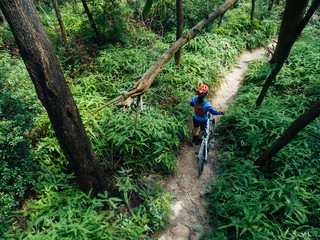 Obraz premium Cross country biking woman cyclist with mountain on tropical forest trail