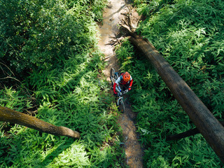 Woman cyclist with a mountain walking on tropical forest