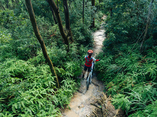 Fototapeta premium Woman cyclist with a mountain walking on tropical forest