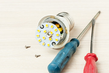 repair broken led light bulb. burned lamp at light wooden background. opened lamp.