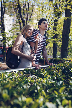 Attractive young couple of tourists admiring view while standing in park