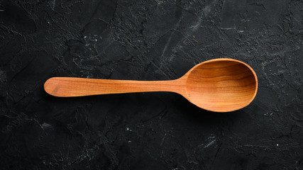 A wooden spoon on a black background. Top view. Free space for your text.